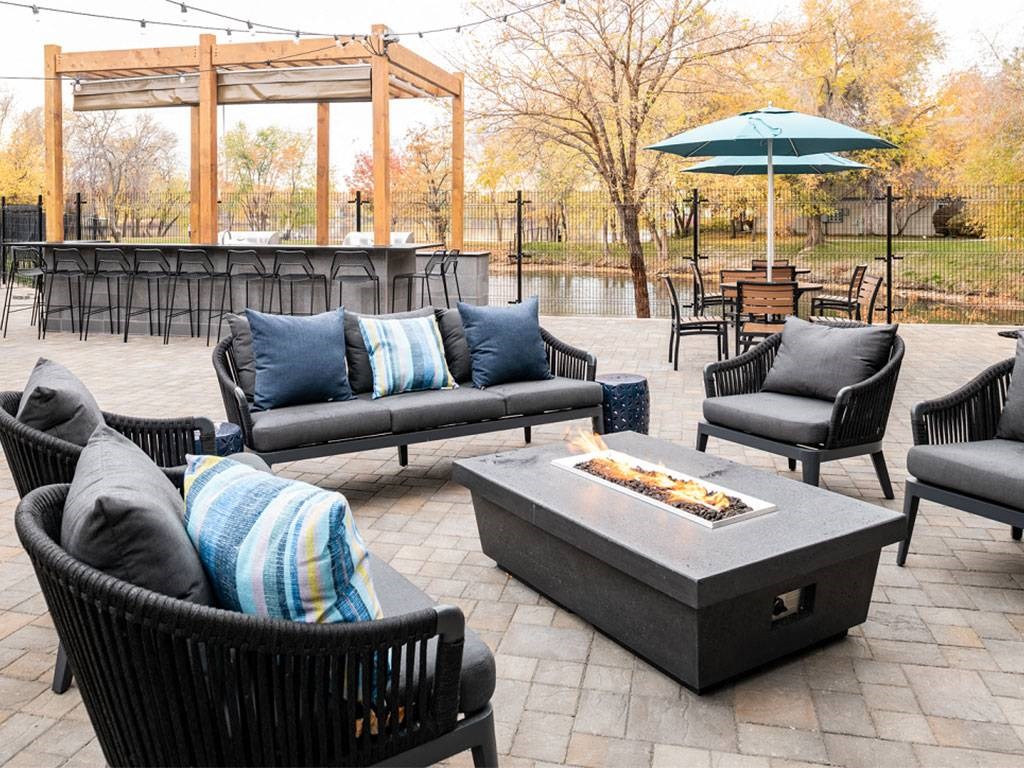 A patio with a fire pit and chairs.