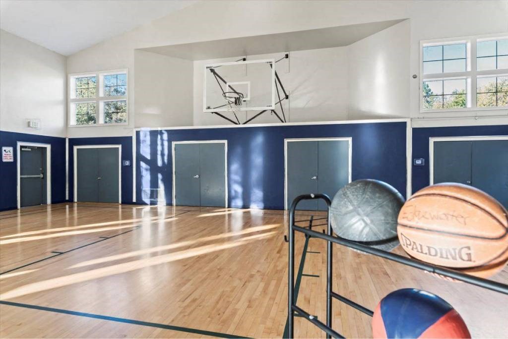 A basketball court with a basketball, a medicine ball, and a volleyball on the rack.
