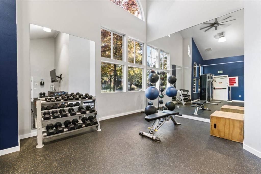 A spacious gym with a variety of equipment including dumbbells, weight benches, and a squat rack.