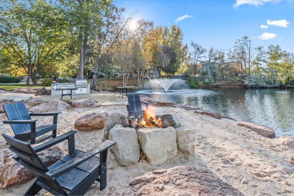 A fire pit sits in the middle of a rocky area next to a body of water.