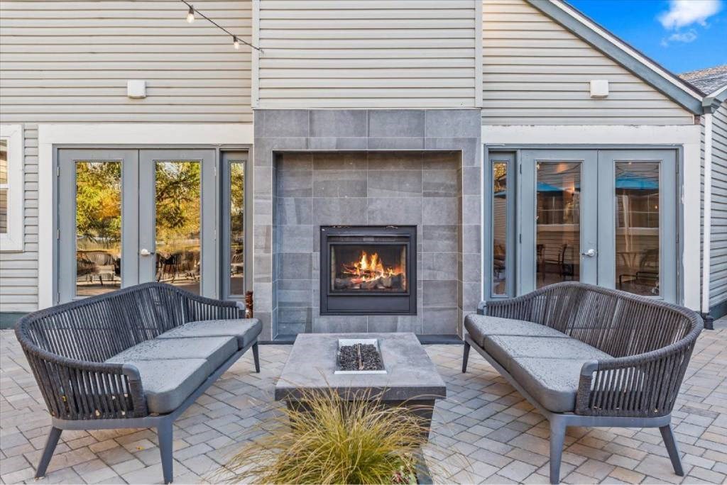 A patio with a fireplace and two chairs.