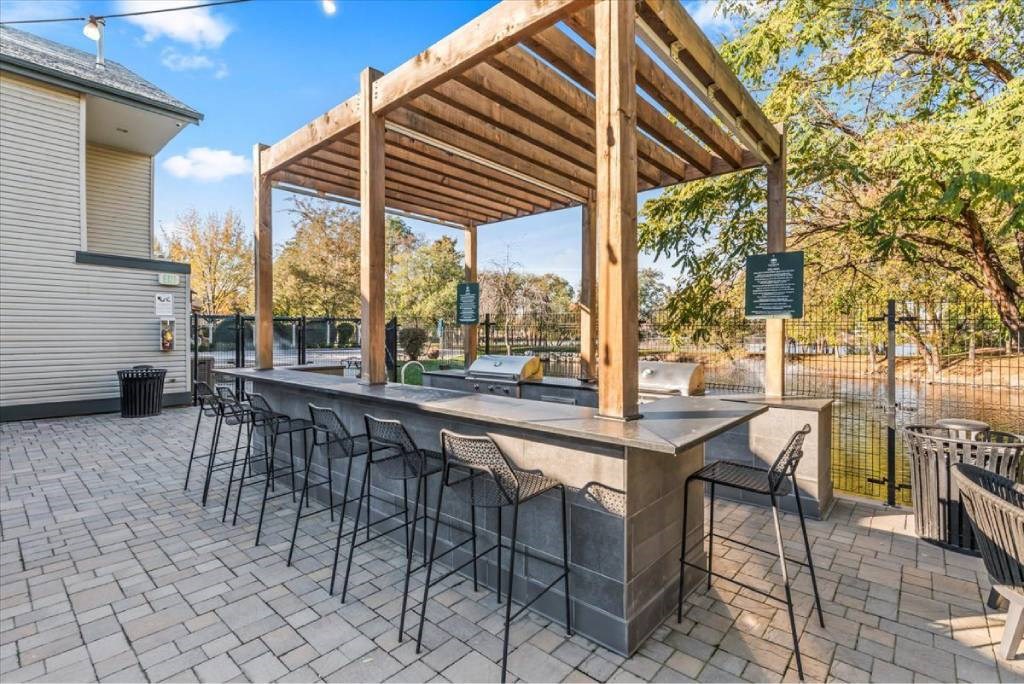 A wooden outdoor bar with a black counter and chairs.