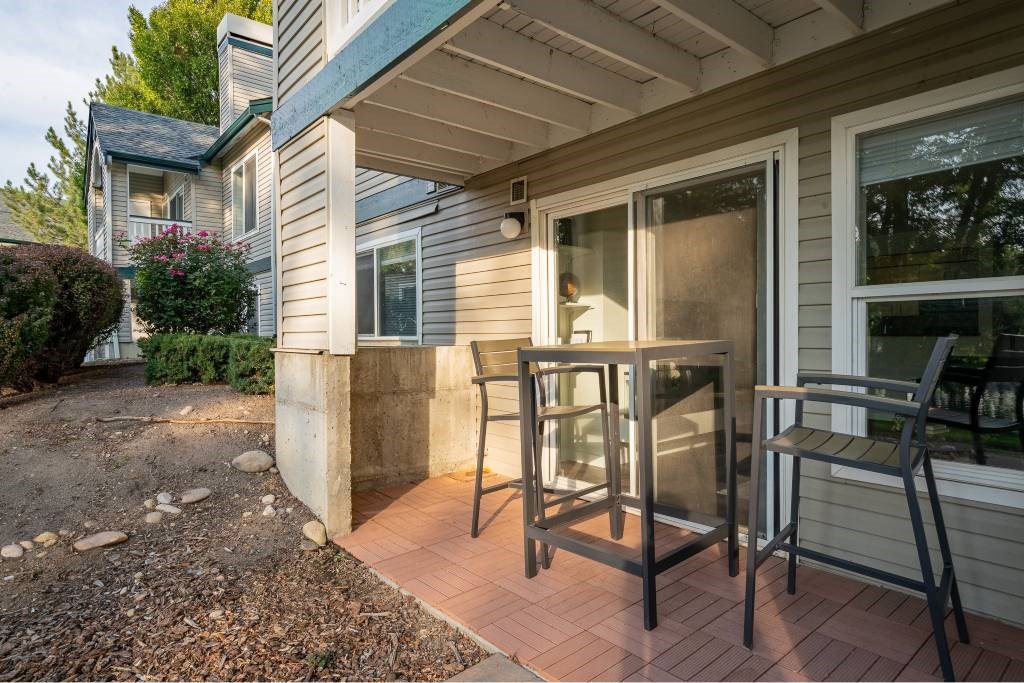 A patio with a table and chairs is in front of a house.