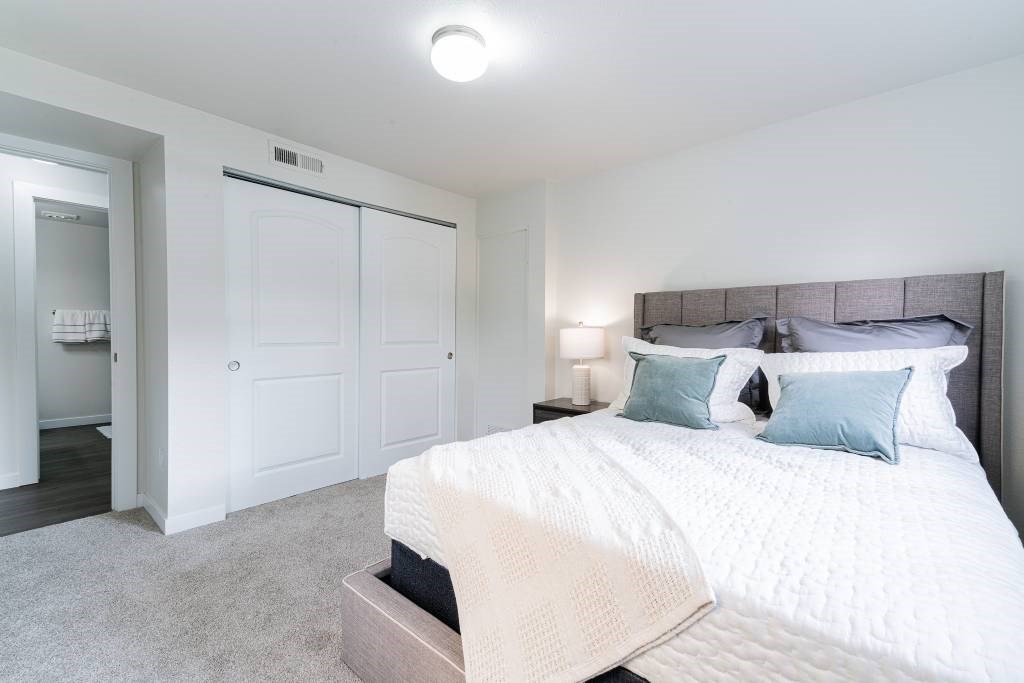 A bedroom with a large bed and a white color scheme.