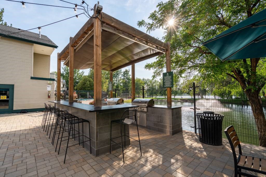 A patio with a bar and chairs is bathed in sunlight.
