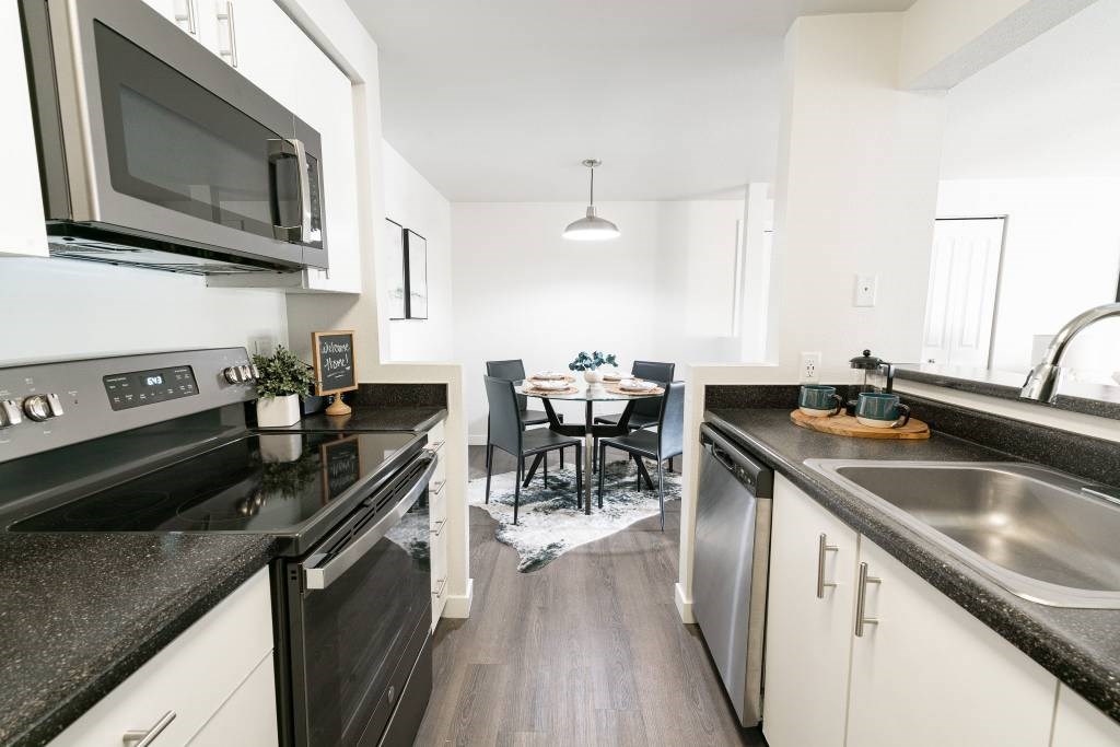 A modern kitchen with black granite countertops and stainless steel appliances.