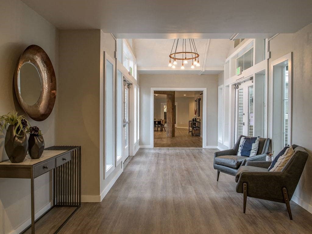 A hallway with a round mirror and a table with vases on it.