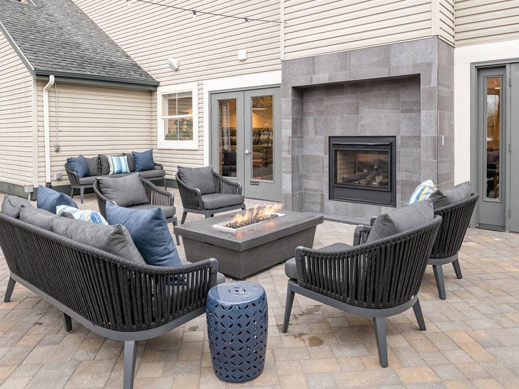 A patio with a fireplace and chairs.