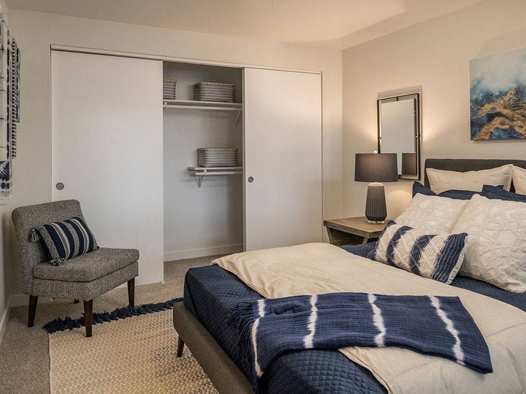 A bedroom with a bed, chair, and a painting on the wall.