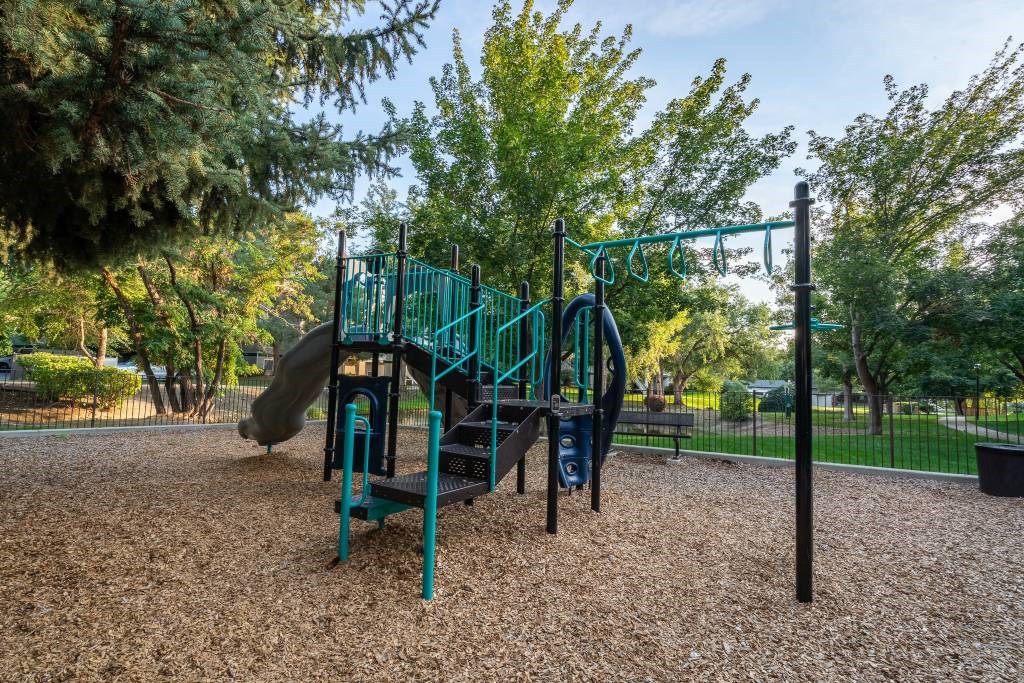 A playground with a green slide and a blue swing set.