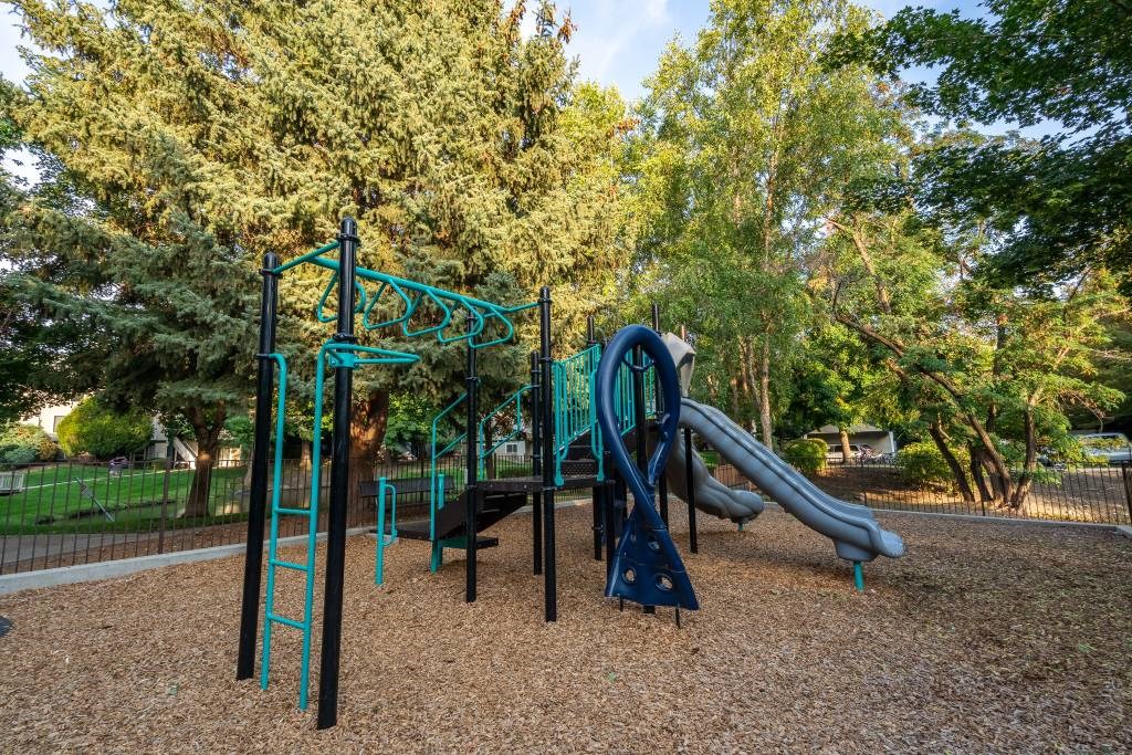 A playground with a green slide and a blue swing set.