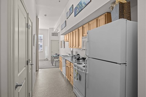 A white refrigerator is in a kitchen with wooden cabinets.
