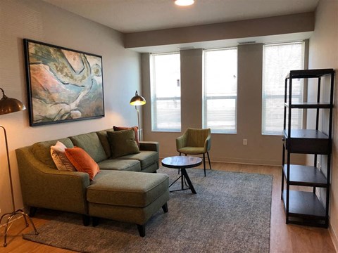 A living room with a green couch, a chair, and a painting on the wall.