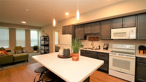 Modern kitchen island and open living area at Morrow Apartments in St. Paul, MN, featuring dark cabinetry