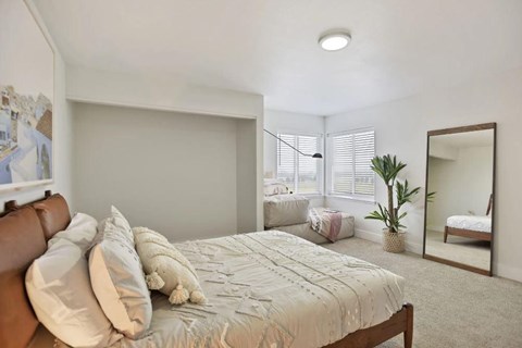 A bedroom with a large bed and a mirror on the wall.