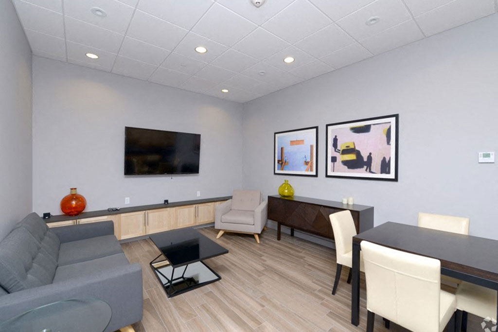 A living room with a grey couch, a black coffee table, and a television mounted on the wall.