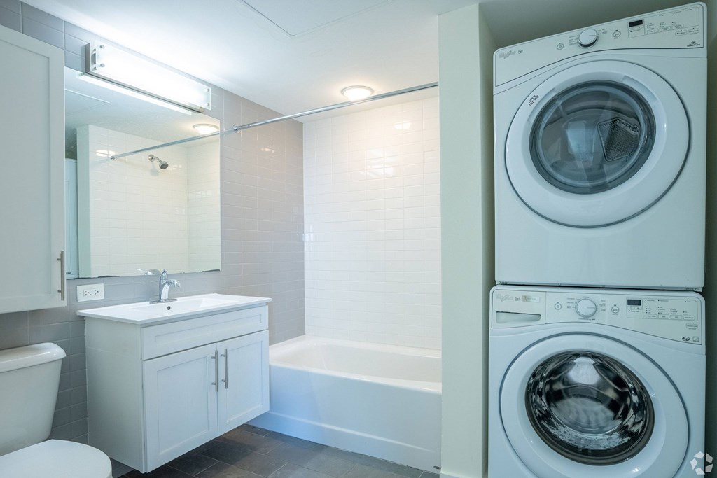 A white washing machine sits next to a white bathtub in a bathroom at 603 Concord Apartments, Cambridge