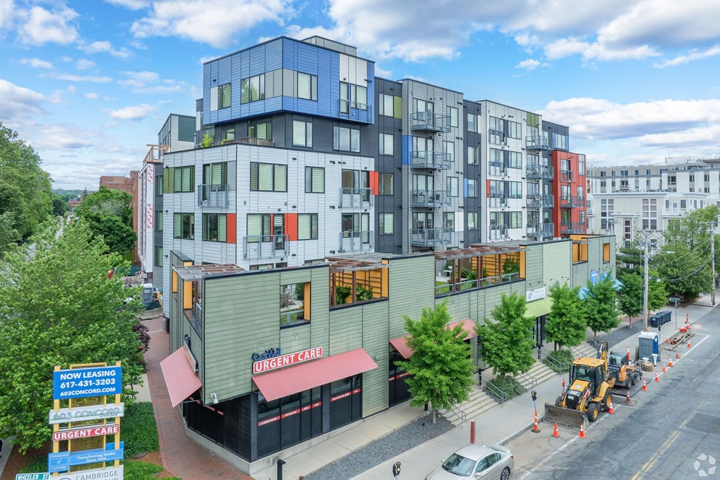 A multi-story building with a green awning and a sign at 603 Concord Apartments, Cambridge, Massachusetts