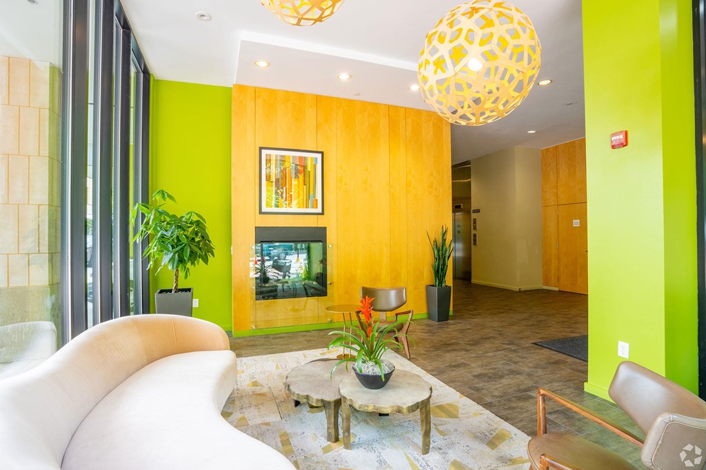 A white sofa sits in a room with a yellow wall and a painting hanging on it. at 603 Concord Apartments, Massachusetts