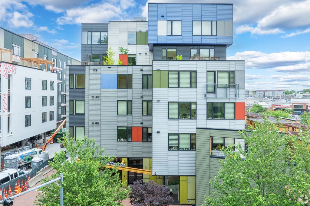 A modern multi-story building with a mix of grey, white, and orange panels. at 603 Concord Apartments, Cambridge 02138