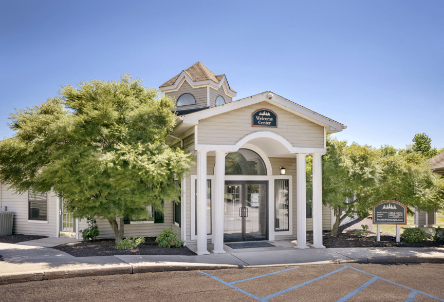 the front of a white church with trees and a driveway