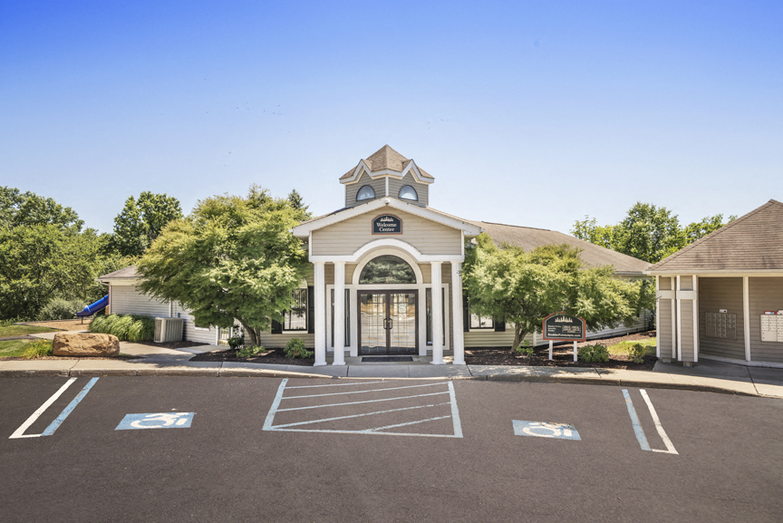 a parking lot in front of a house with a driveway and a white building
