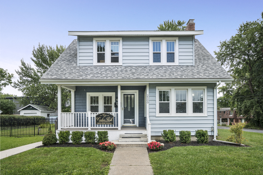a blue house with a lawn and a sidewalk in front of it