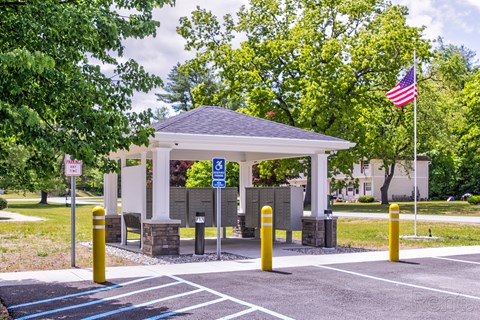 A gazebo is surrounded by a parking lot with a flag flying in the background.