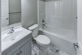 A white toilet sits next to a white sink in a bathroom.
