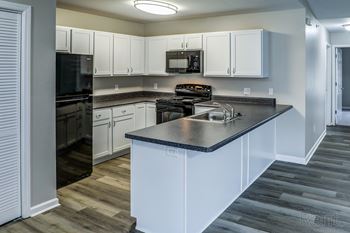 A kitchen with white cabinets and a black countertop.