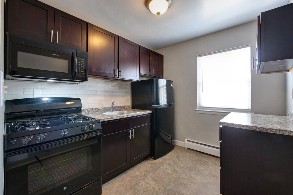 A kitchen with black appliances and brown cabinets.