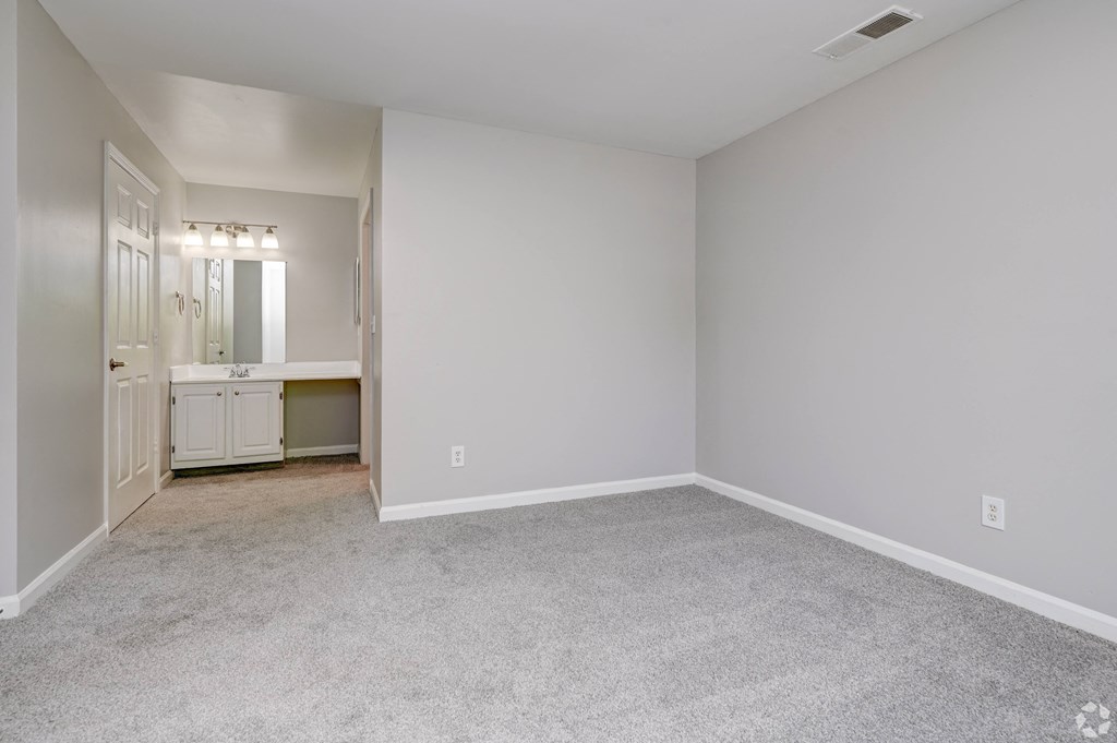 a bedroom with white walls and carpet and a bathroom