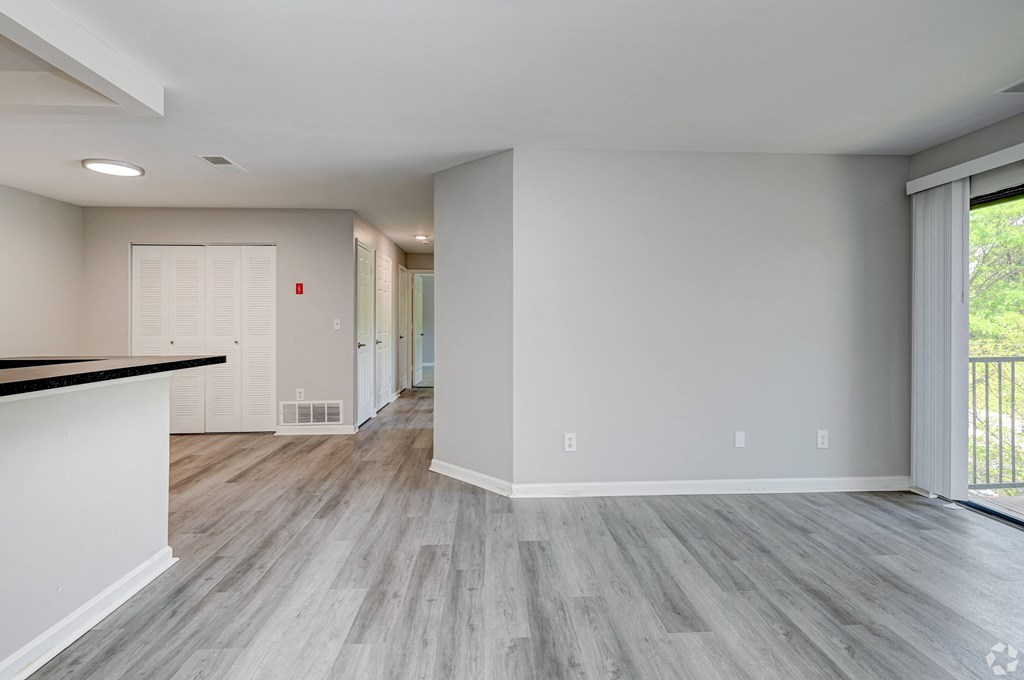 an empty living room and kitchen with wood flooring and a large window