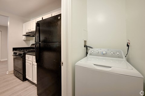 a white washer and dryer in a kitchen with a black refrigerator and