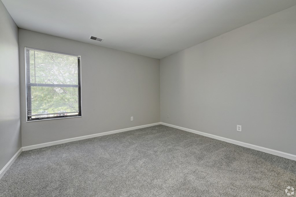 an empty room with a window and carpet