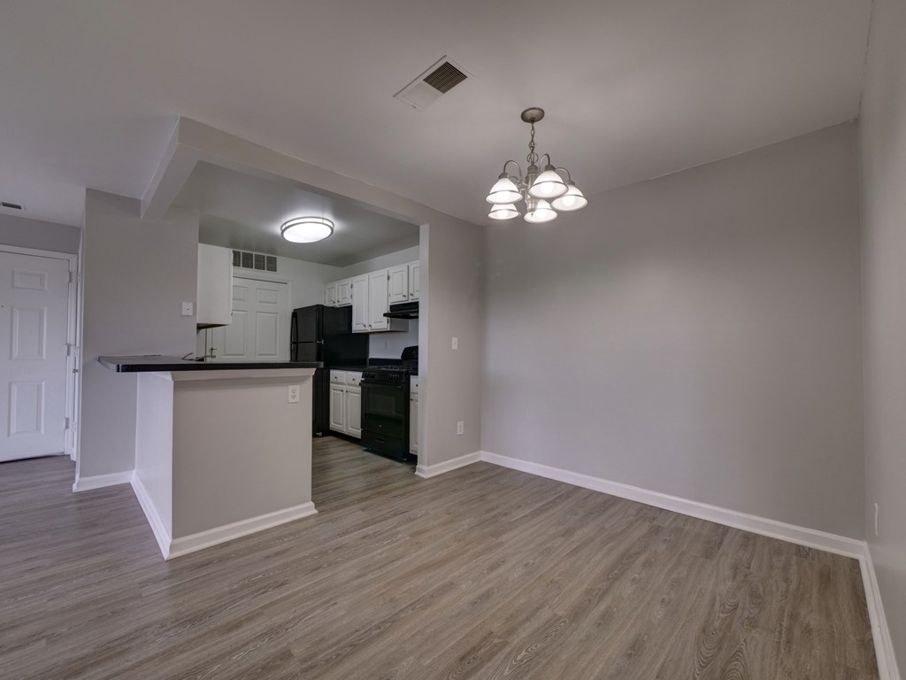 an empty living room with a kitchen with a black counter top