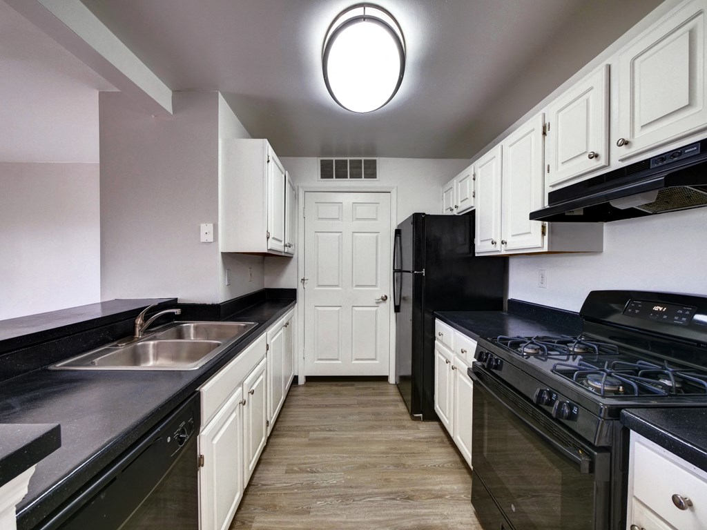 a kitchen with black counters and black appliances and white cabinets