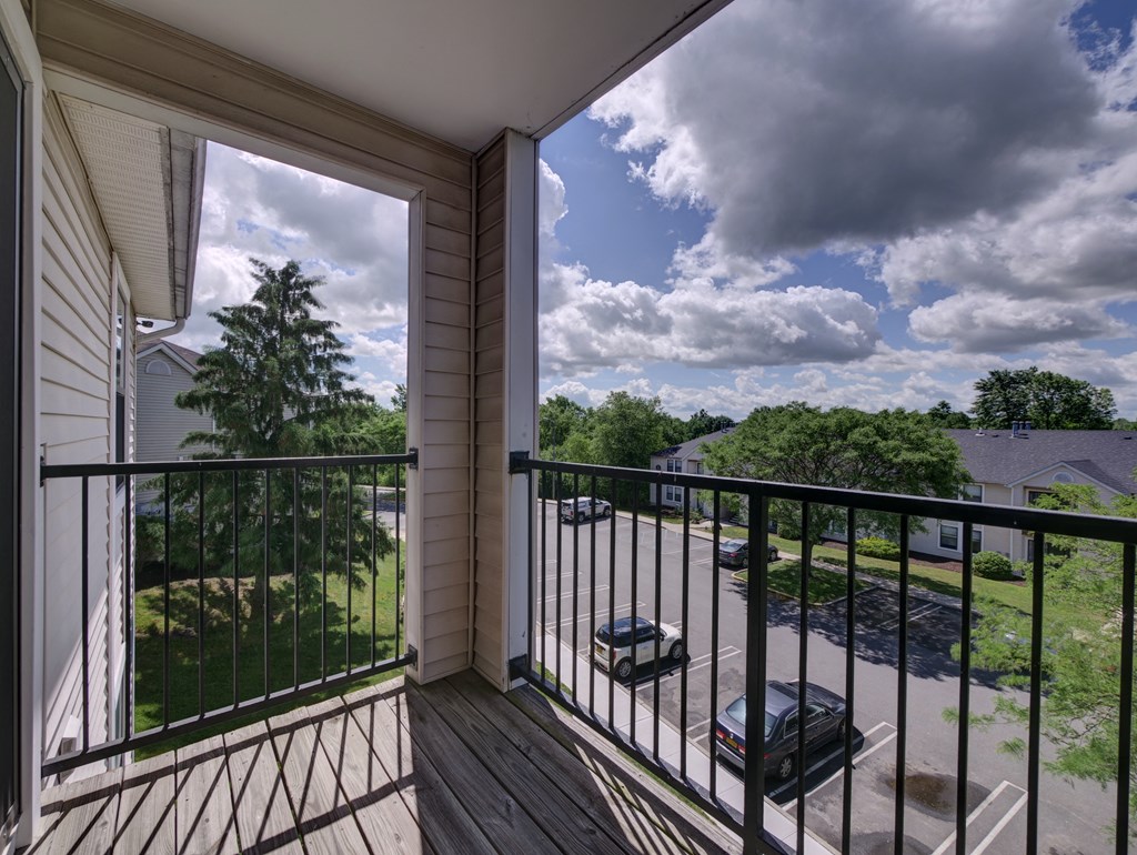a balcony with a view of a yard and a cloudy sky