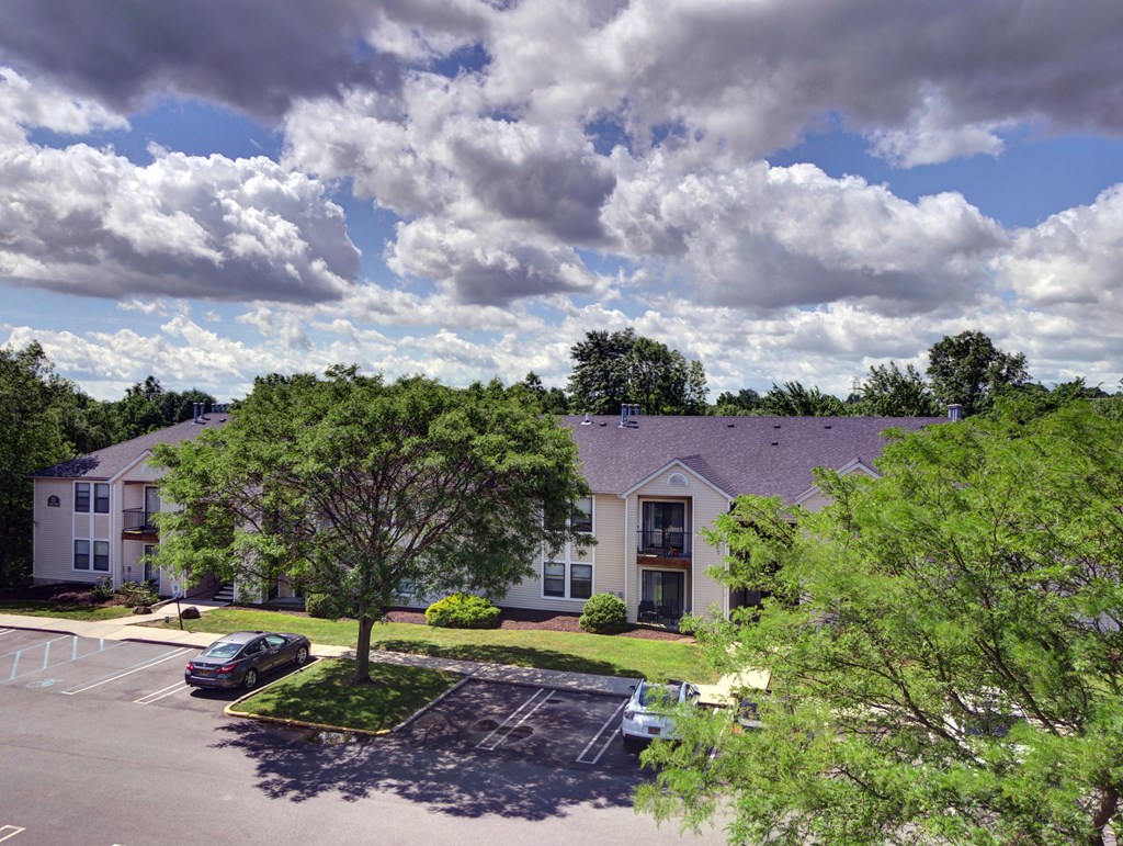 an aerial view of a building with a parking lot and trees