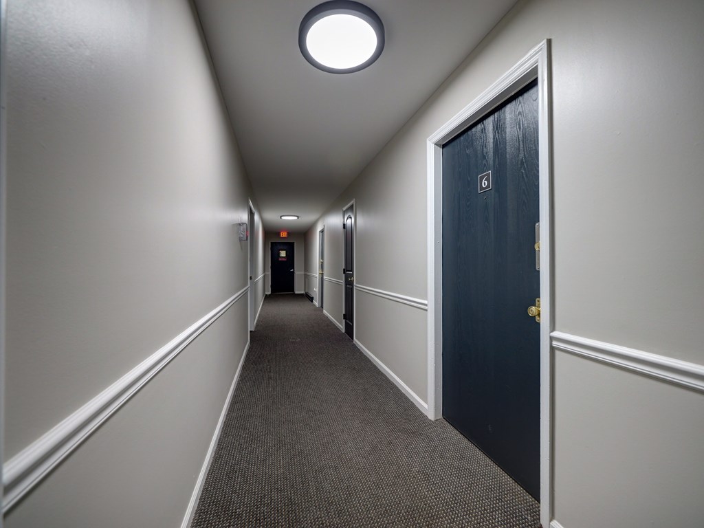 A hallway with a blue door and a light on the ceiling.