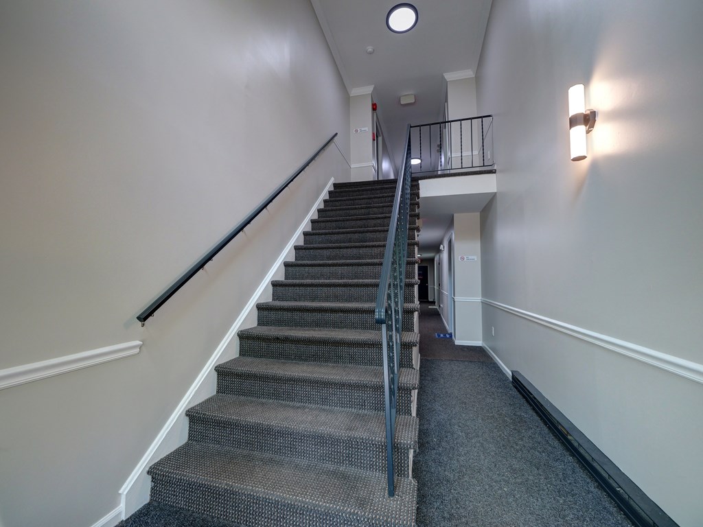 A staircase with a metal railing and a carpeted floor.
