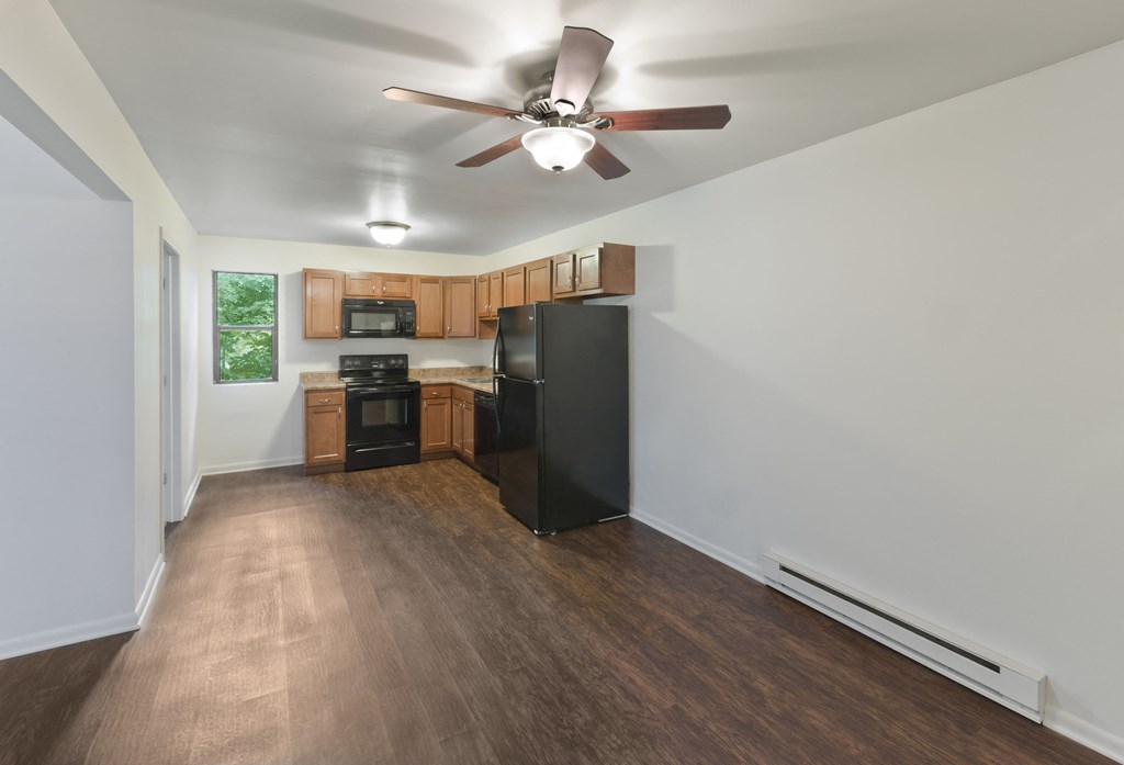 an empty living room and kitchen with a ceiling fan