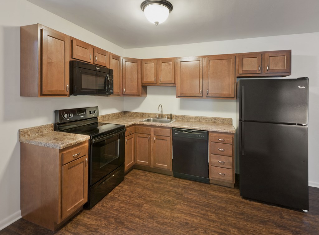 an empty kitchen with black appliances and wooden cabinets