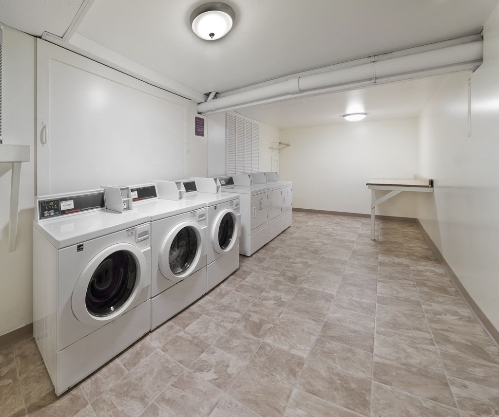a laundry room with washers and dryers and a row of washing machines