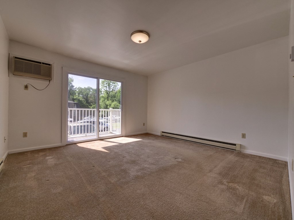 an empty living room with a sliding glass door to a balcony