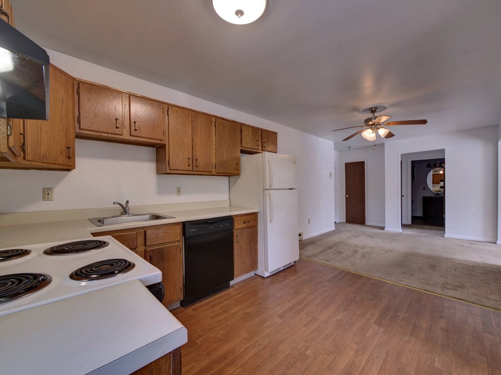 an empty kitchen and living room with wood flooring and white appliances