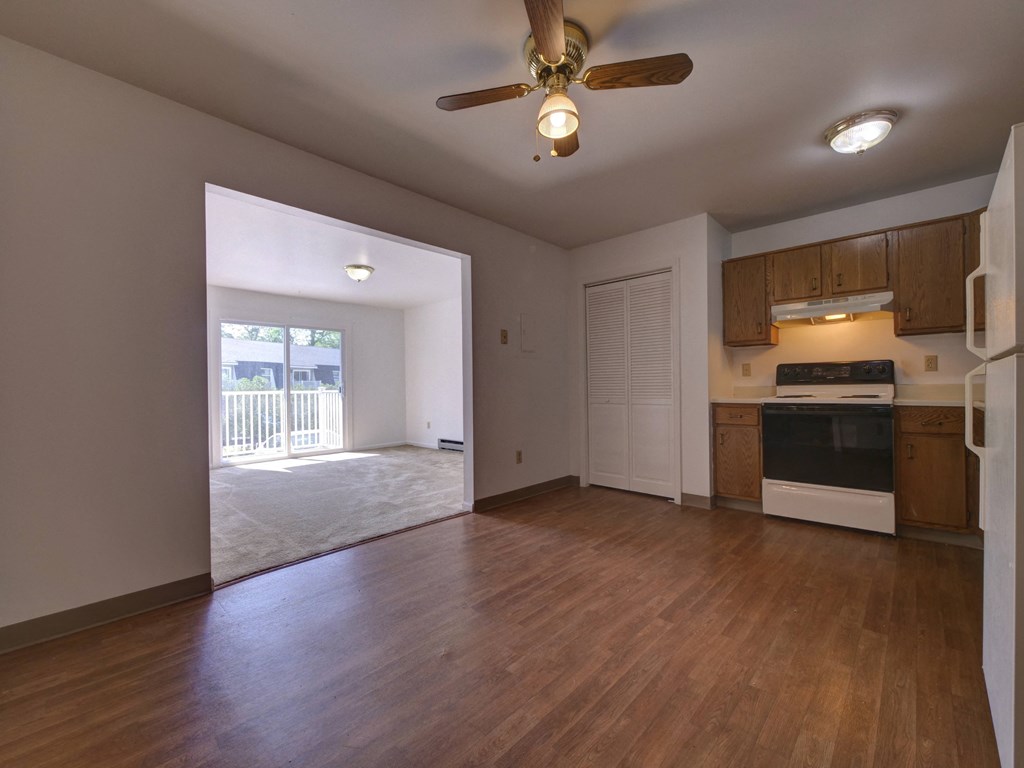 an empty living room and kitchen with a ceiling fan
