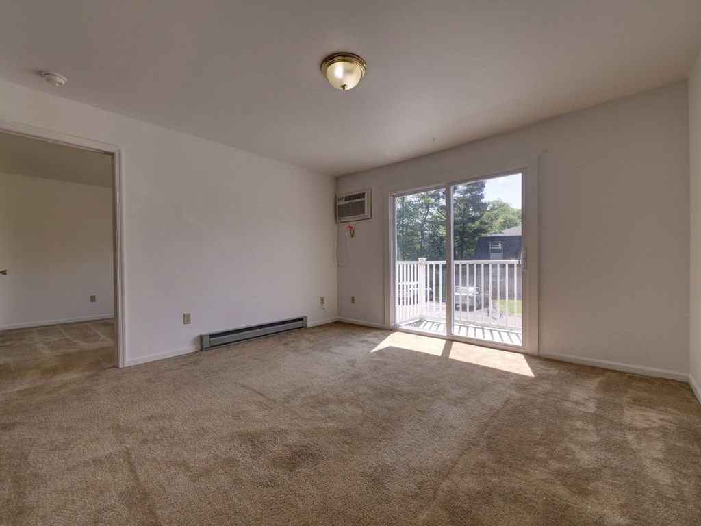 an empty living room with a sliding glass door to a balcony