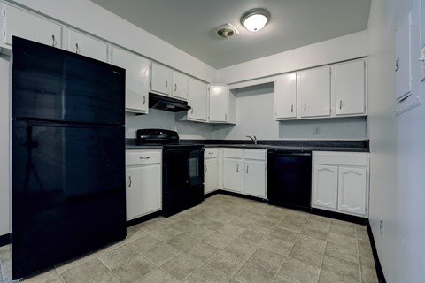 A kitchen with black appliances and white cabinets.