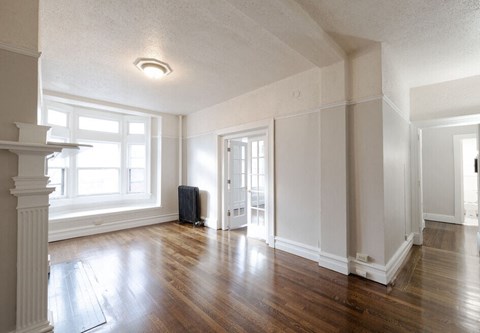 an empty living room with wood floors and a window